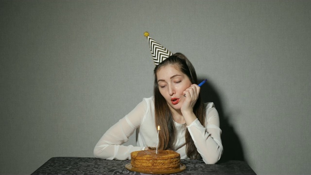 独自忧伤的女孩庆祝节日，他独自坐在桌子旁，桌上放着蛋糕和蜡烛视频素材