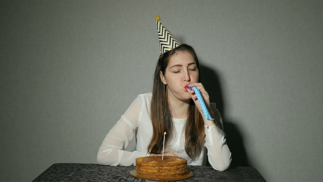 独自一人的女孩庆祝节日，他独自坐在桌前，桌上放着蛋糕和蜡烛视频素材