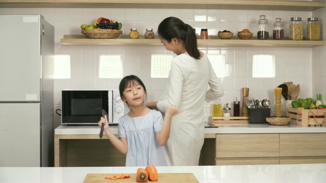 女儿在跳舞，而怀孕的母亲在厨房做饭视频素材