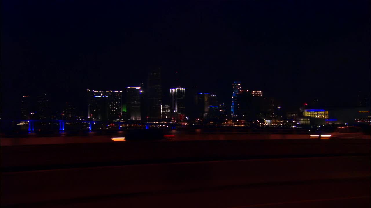 侧面视角从汽车行驶在高速公路在夜间，城市天际线为背景，迈阿密，佛罗里达州，美国视频素材