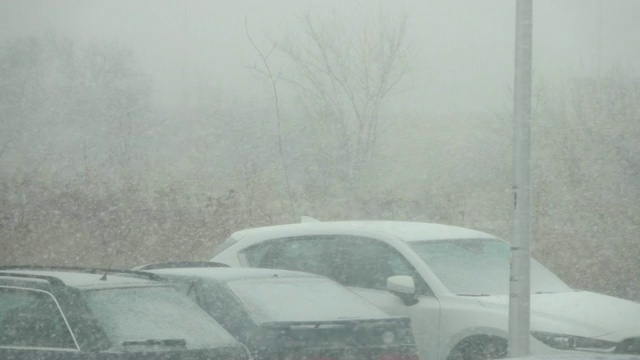 市中心有暴风雪。城市里被雪覆盖的汽车。城市下雪，清晨，窗外景色。雪。的树木,汽车。视频素材