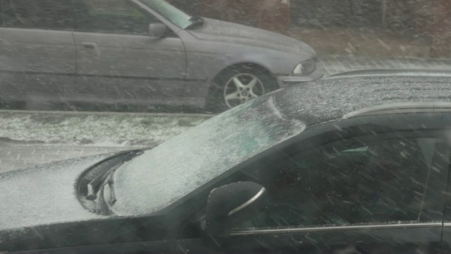 市中心有暴风雪。城市里被雪覆盖的汽车。城市下雪，清晨，窗外景色。雪。的树木,汽车。视频素材