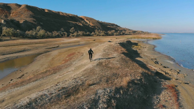 在秋日的湖边，人们骑着山地车。从无人机拍摄视频素材