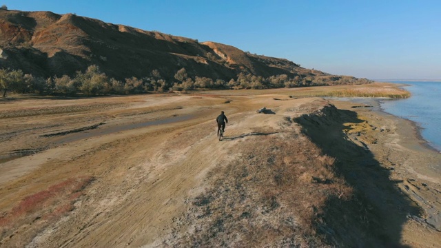 在秋日的湖边，人们骑着山地车。从无人机拍摄视频素材