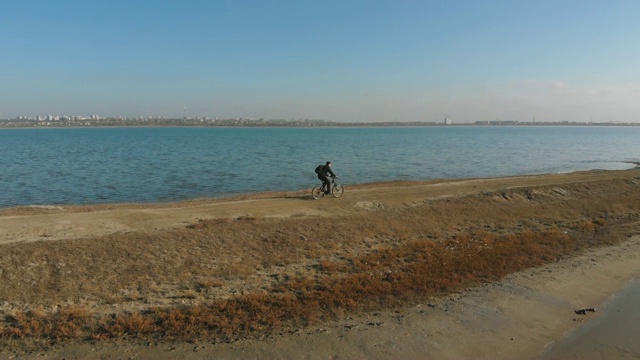 在秋日的湖边，人们骑着山地车。从无人机拍摄视频素材