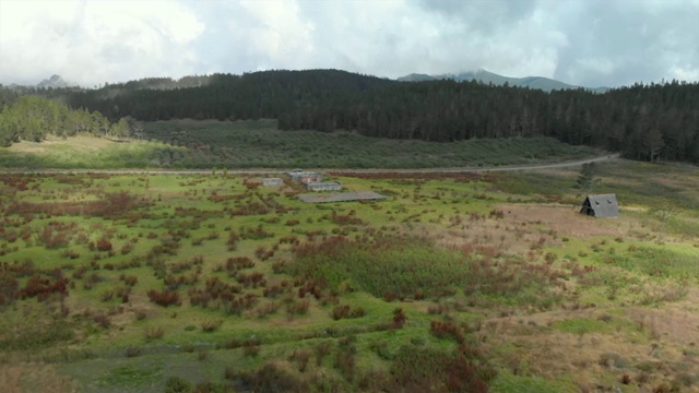 空中向后:年轻男子在风景废墟小屋前，旁边是其他废墟视频素材