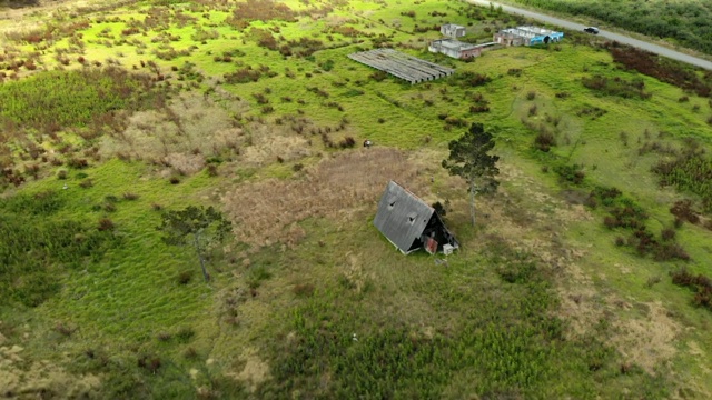 航拍:森林中草地上的其他建筑旁边的风景优美的废墟小屋视频素材