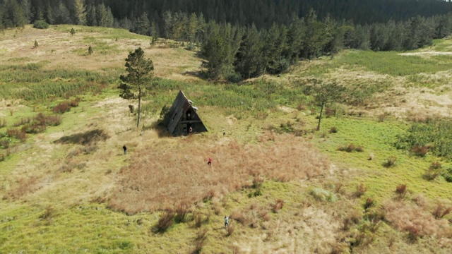 空中:年轻的女人和男人在草地上的废墟小屋视频素材