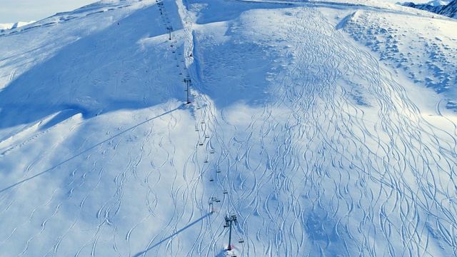 在滑雪缆车和滑雪斜坡上的滑雪者上方架空。在雪山滑雪缆车的视野。冬季滑雪和单板滑雪的好天气。视频素材