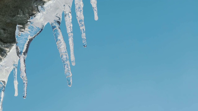 屋顶上的冰柱在蓝天的映照下融化了视频素材