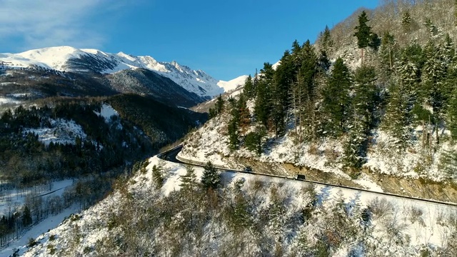 雪山上的极限之路。空中拍摄的汽车在冬天。鸟瞰图一辆车在山路上，在一个晴朗的日子。法国的山脉被雪覆盖着。寒假的好天气视频素材