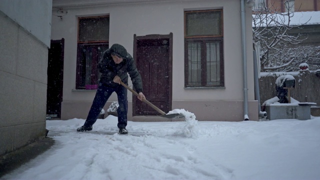 一位年长男子在后院除雪的广角镜头视频素材