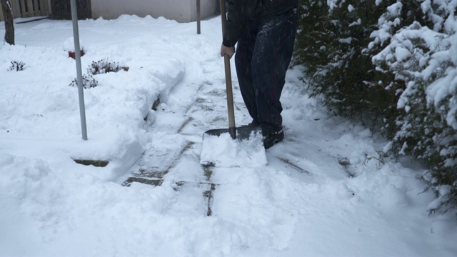 一位老人正在清理前院人行道上的积雪视频素材