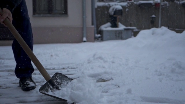 一个年长男子铲雪从他的后院的特写视频素材