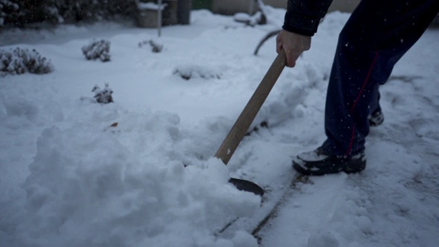 一个老年人在他的院子里铲雪的特写视频素材