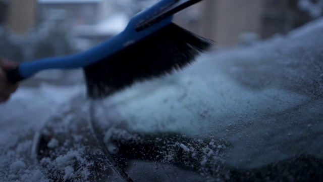 一个高级男子清理他的车雪的特写视频素材