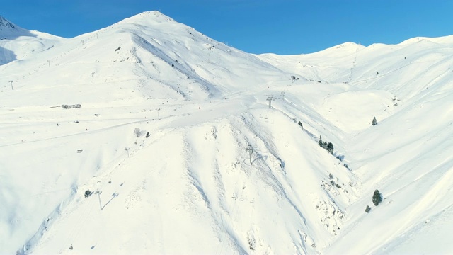 鸟瞰图滑雪缆车在一个白色的雪山，在滑雪胜地与滑雪缆车在山下蓝天，在法国。冬天滑雪的好天气。视频素材