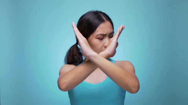 严肃的女人挥舞手指，没有手势，看着摄像头在孤立的蓝色背景4k视频素材