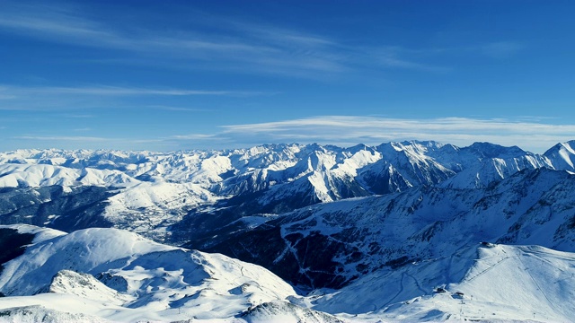 美丽的鸟瞰滑雪场在蓝天下的冬季。法国的山顶被雪覆盖着。冬天的白色风景令人放松，非常适合极限运动。视频素材