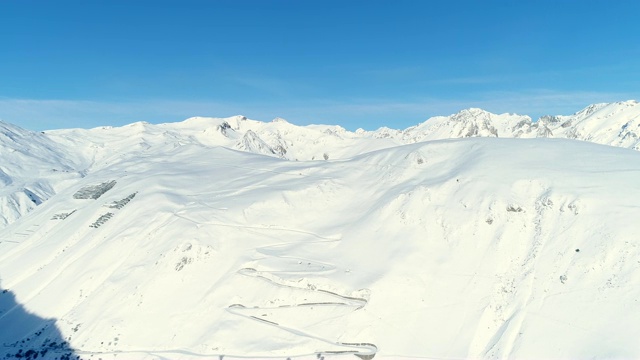 飞过雪谷。蓝天下的山景鸟瞰。法国的山顶被雪覆盖着。冬天令人放松的白色风景。视频素材