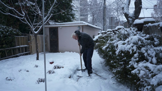 一个老人在前院用雪铲铲雪视频素材