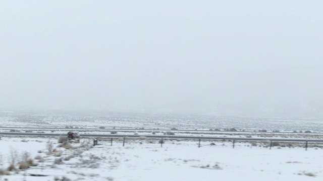 无人机拍摄的汽车和卡车沿着公路行驶在一个雪域沙漠景观在一个阴天的冬天视频素材