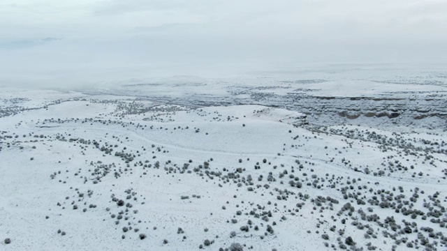 头顶无人机拍摄的雪道蜿蜒穿过岩石沙漠景观在一个阴天的冬天视频素材