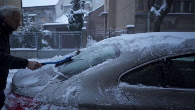 一位老人正在清除车上的积雪视频素材