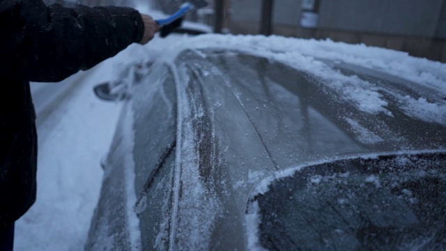 一位老人正在清理车顶的积雪视频素材