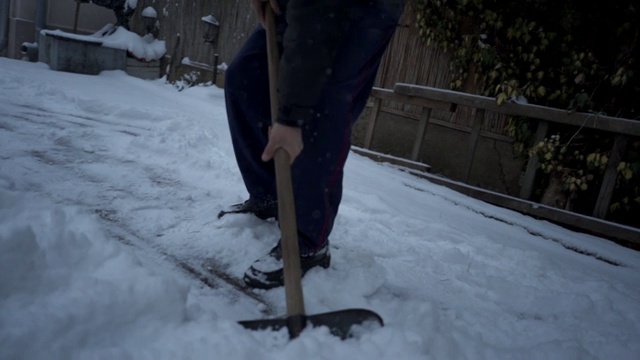 一个老人在后院用雪铲铲雪视频素材