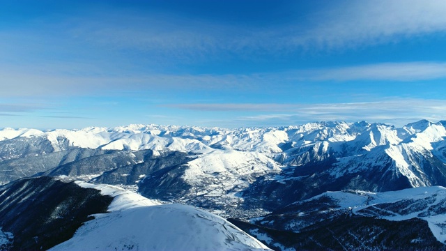 令人惊叹的空中冬雪滑雪场与雪山在蓝天下。法国的山顶被雪覆盖着。冬天令人放松的白色风景。视频素材