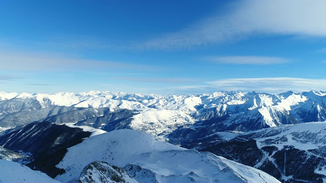 空中飞行，在蓝天下，飞越令人惊叹的岩石峰和雪山。法国的山顶被雪覆盖着。冬天令人放松的白色风景。视频素材