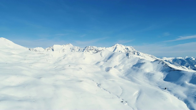 在蓝天下，用无人机飞越雪山。法国的山顶被雪覆盖着。冬天的白色风景令人放松，非常适合极限运动。视频素材