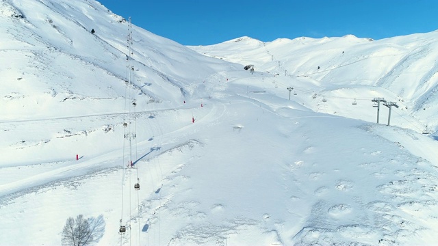 雪山上滑雪道和滑雪缆车的空中天线。冬季滑雪和单板滑雪的好天气。视频素材