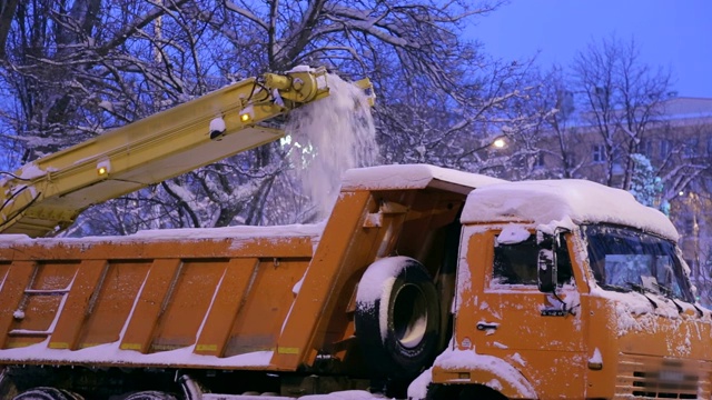 特写专用扫雪机将雪卸载到卡车上。雪在户外犁。视频素材