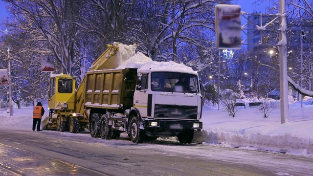 特写专用扫雪机将雪卸载到卡车上。雪在户外犁。视频素材