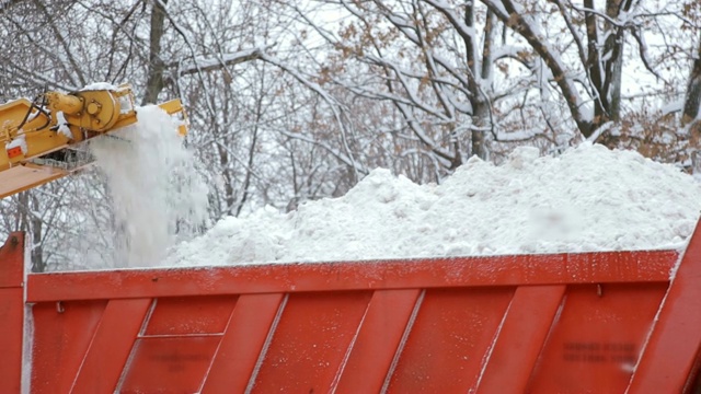 特写专用扫雪机将雪卸载到卡车上。雪在户外犁。视频素材