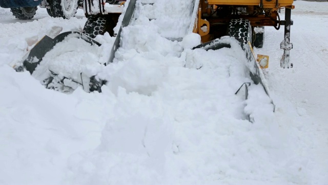 在暴风雪中用扫雪机从街道上清除积雪的拖拉机。视频素材