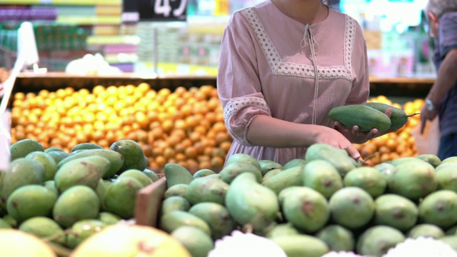 年轻女子在超市选择了水果和购物视频素材