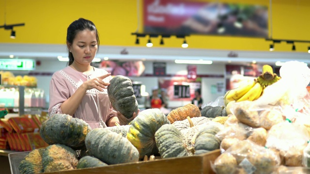 年轻女子在超市选择了水果和购物视频素材