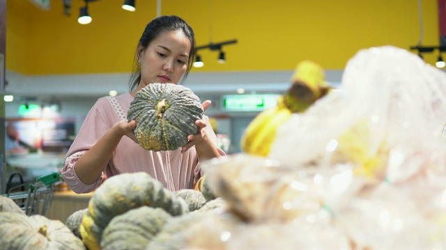 年轻女子在超市选择了水果和购物视频素材