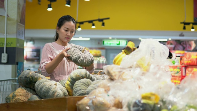 年轻女子在超市选择了水果和购物视频素材