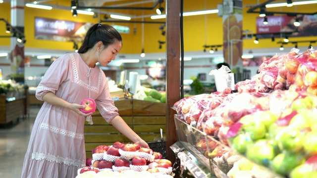 年轻女子在超市选择了水果和购物视频素材