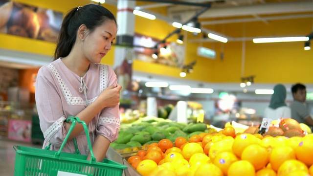 年轻女子在超市选择了水果和购物视频素材