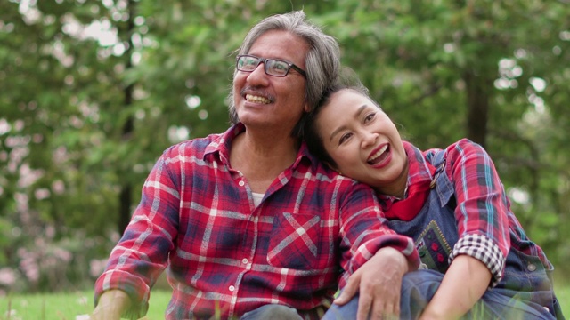 年老的亚洲夫妇坐在花园里愉快地交谈。视频素材