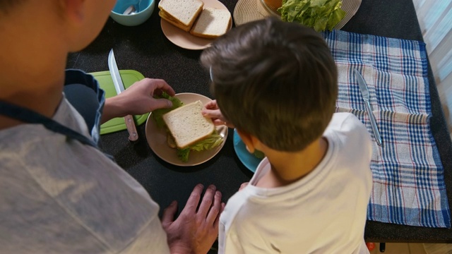 男人和男孩一起拿产品，一起准备三明治视频素材