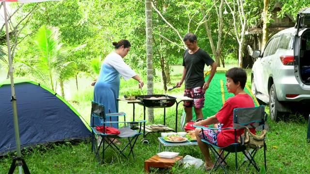 一家人乘车旅行，在假期露营，在帐篷里休息，在森林里吃烤海鲜。视频素材