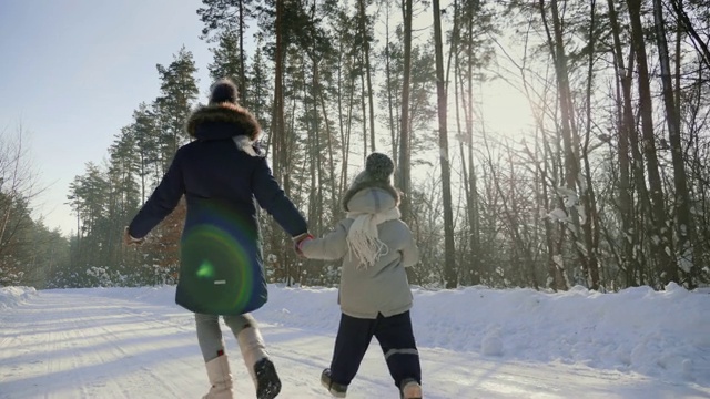 两个小孩在雪地上逃跑的背影视频素材