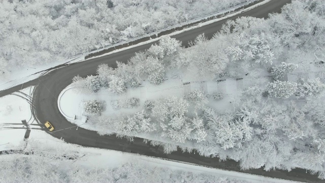 鸟瞰图转向公路在山区冬季积雪覆盖森林视频素材