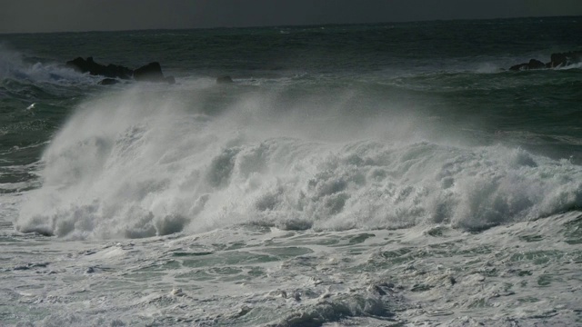 巨大的海浪。狂暴狂暴的海洋猛烈地拍打着布满泡沫的海浪，冲击着岩石的海岸。UHD视频素材